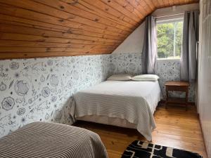 a bedroom with two beds and a wooden ceiling at Casa Cerejeiras in Campos do Jordão