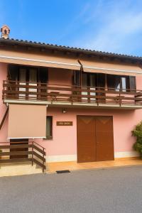 a pink house with brown doors and a balcony at Hiša Vanda in Dobrovo