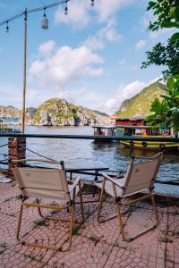 two chairs and a table next to a body of water at Tsunami bungalow in Cat Ba