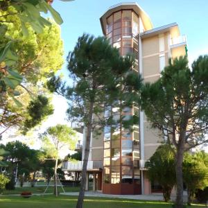 ein hohes Gebäude mit Bäumen davor in der Unterkunft Studio in Porto Santa Margherita 40176 in Porto Santa Margherita