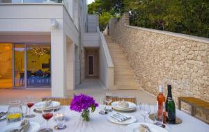 ein Tisch mit Weingläsern und lila Blumen darauf in der Unterkunft Stunning Brac Villa 5 Bedrooms Villa Selca Brac 5 Metres To The Beach Private Swimming Pool Selca in Selca
