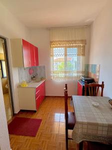 a kitchen with red cabinets and a table and a table and a dining room at Hotel Martini in Velipojë