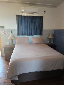 a bedroom with a large white bed with a blue curtain at Sunrise Beach Lodge in Ponta Malongane +29 photos