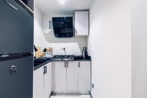 una cucina con mobili bianchi e un frigorifero nero di Cozy 1 Bedroom Apartment a Lekki