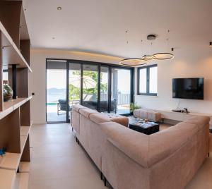 a living room with a large couch and a television at Villa Blue Sunset - Stunning Sea View Luxury Villa with Private Heated Pool in Brsečine