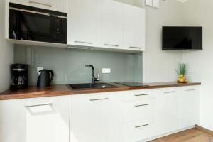 a white kitchen with a sink and a microwave at Family Apartment Puck Closeto the Sea by Noclegi Renters in Puck
