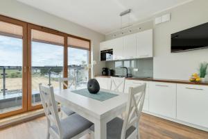 a kitchen with a white table and chairs and a window at Family Apartment Puck Closeto the Sea by Noclegi Renters in Puck