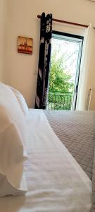 a bedroom with a large white bed and a window at Sofia's Home 9min. Athens Airport in Artemida