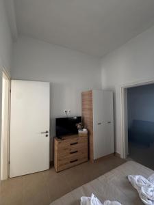 a white room with a tv and a dresser and a bedroom at Nikistratos Cozy Apartment in Néa Alikarnassós
