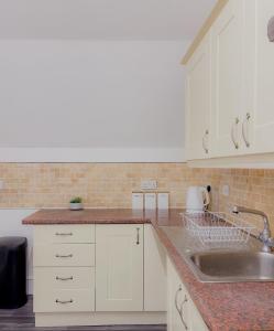 a kitchen with white cabinets and a sink at Euston Road - Beach Apartment 4 in Great Yarmouth