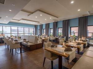 a restaurant with tables and chairs and windows at Hotel Innsento - Health Campus Passau in Passau