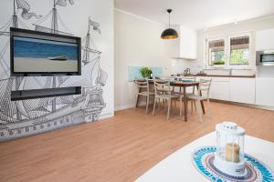 a kitchen and dining room with a tv on a wall at Apartamenty, Domki i Pokoje ze śniadaniem Kajan in Jastrzębia Góra