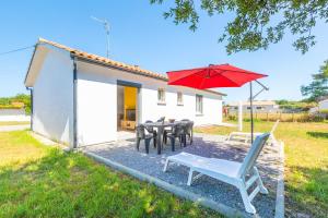 un ombrello rosso e un tavolo e delle sedie con un tavolo e una panca di Gemma - 5 min de la Plage a Ondres