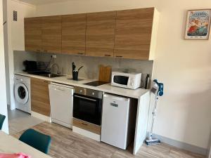 a small kitchen with a microwave and a dishwasher at Résidence les goélettes studio l escale in Houlgate +3 photos