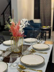 a table with white plates and a vase of flowers at 2 Storey Family House in Casa Verde Mati City in Mati