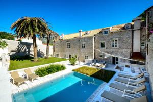 a house with a swimming pool and chairs and a palm tree at Luxury Dubrovnik Villa 6 Bedrooms Villa Gomila Perfect For Larger Groups in Zaton