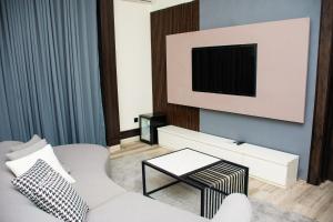 a living room with a white couch and a tv at The Thribeka International Hotel Asaba in Asaba