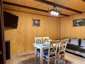 a dining room with a table and chairs and a television at Dimira Котедж з басейном in Slavske