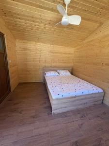 a wooden room with a bed and a ceiling fan at Camping mery in Murighiol