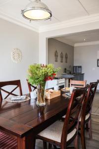 a dining room table with a vase of flowers on it at Upper House Boutique Guesthouse in Clarens