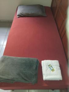 a bed with red sheets and a towel on it at Hospedagem Sousa Santos in Montes Claros