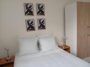 a bedroom with a white bed with four pictures on the wall at Modern apartment! in Hazebrouck