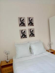 a bedroom with a white bed with four pictures on the wall at Modern apartment! in Hazebrouck