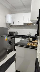 a kitchen with white cabinets and a sink and a dishwasher at Corniche House in Nador +8 photos