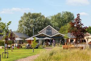 a large building with people sitting in the grass at Robins Retreat ML55 Lower Mill Estate Cotswolds in Somerford Keynes