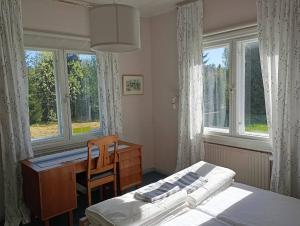 a bedroom with a desk and a bed and windows at sydtorp charming old house in the countryside in Rosendal