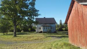 a white house with a tree and a red barn at sydtorp charming old house in the countryside in Rosendal