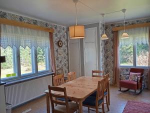 a dining room with a table and chairs and windows at sydtorp charming old house in the countryside in Rosendal +8 photos