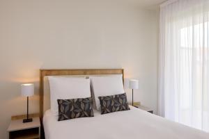 a bedroom with a large white bed with two pillows at Zenitude Hôtel-Résidences Le Havre Les Docks in Le Havre