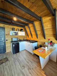 a kitchen with a table and a wooden ceiling at Chalé com Hidromassagem, Lareira e Piscina na Beira da Lagoa in Imaruí