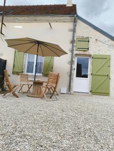 a patio with a table and chairs and an umbrella at Gite l'ancien four à pain calme et douillet in Breteau