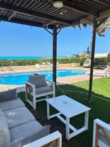 a patio with a couch and a table and a pool at فيلا اول صف بحر مارينا الساحل الشمالي العلمين برايفت بول in El Alamein