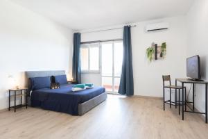 a bedroom with a blue bed and a large window at Leonardo Da Vinci Guest House in Fiumicino
