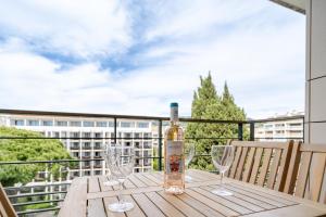 una bottiglia di vino seduta su un tavolo di legno con bicchieri di Résidence Carlton Riviera - Cannes a Cannes Altre 55 foto
