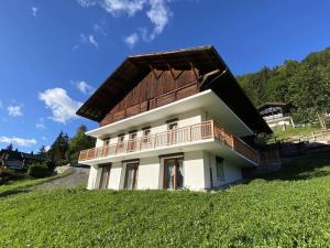 a house with a wooden roof on a green field at Chalet 6 pièces neuf, 12 pers, 3 sdb, parking, terrasse, proche remontées - FR-1-676-193 in Châtel