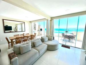 - un salon avec un canapé et une salle à manger donnant sur l'océan dans l'établissement Luxuosa Cobertura Vista Mar- Praia Grande, à Arraial do Cabo