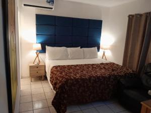 een slaapkamer met een groot bed met een blauw hoofdeinde bij bamboo bed and breakfast in San Pedro Sula
