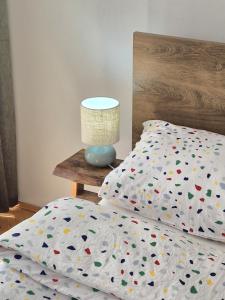 ein Bett mit einer Bettdecke und einer Lampe auf einem Tisch in der Unterkunft Apartman Pasarela - mirna lokacija u centru in Bihać