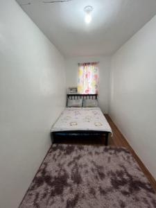 a small room with a bed and a rug at Juriz staycation Place in Santo Tomas