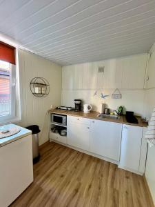 a kitchen with white cabinets and a wooden floor at Beach House Mrzeżyno in Mrzeżyno