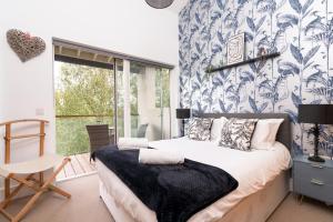 a bedroom with a bed with a blue and white wallpaper at Ducklings CW65 Lower Mill Estate Cotswolds in Somerford Keynes