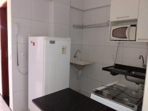 a kitchen with a white refrigerator and a microwave at Brisa Brasil Residence in Fortaleza