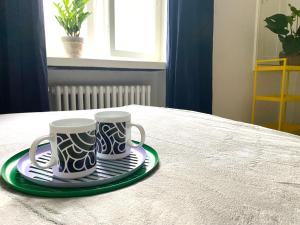 two coffee mugs on a plate on a table at Simply chic Kamppi !NEW! in Helsinki