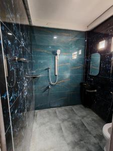 a blue tiled bathroom with a shower and a toilet at Marutham Farm House in Jaffna +13 photos