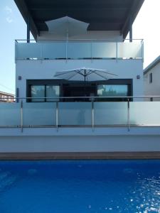 a house with a swimming pool and an umbrella at Presciosa Villa Jupiter SOLO FAMILIAS in Cambrils