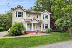 une maison avec un banc rouge dans la cour avant dans l'établissement Dogwood Cottage, à Bar Harbor